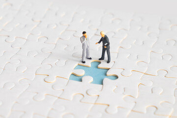 Miniature people looking for a jigsaw puzzle solution to a missing piece problem.