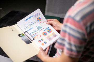 Accountant working at home at night, casual financial investment on a calculator, calculating, analyzing business and marketing growth on various financial document data graphs.