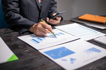 Accountants working on financial investments on calculators, calculating, analyzing business and marketing growth on graphs of various financial documents.