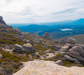 Mountain landscape from the summit of La Maliciosa with impressive rock formations, wild vegetation, and a partly cloudy sky. Panoramic view of the Navacerrada Reservoir, perfect for hiking.