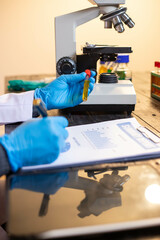 Human hand in glove holding glass jar in modern laboratory. Close-up and long exposure photography.