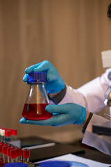 Human hand in glove holding glass jar in modern laboratory. Close-up and long exposure photography.
