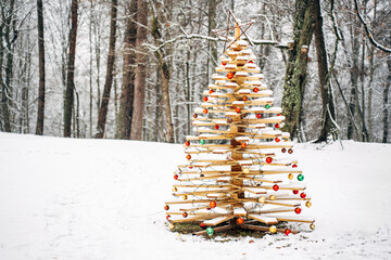 beautiful handmade wooden Christmas tree decorated with festive balls in a snowy forest
