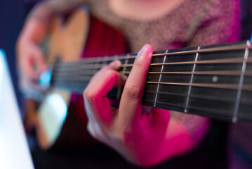 Professional Women Musician composing a song with acoustic guitar, piano keyboard and condenser microphone. She mixing and mastering her song with table at digital recording home studio.