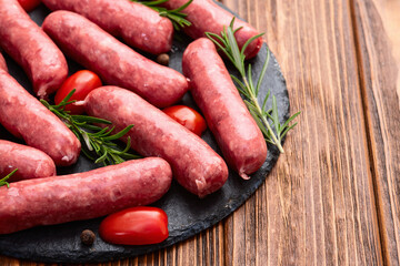 Raw beef sausages with rosemary and tomatoes photography . Top view