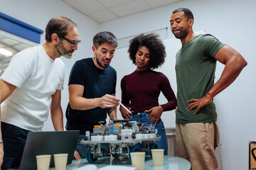 Engineers team analyzing electric circuit of robot prototype in laboratory