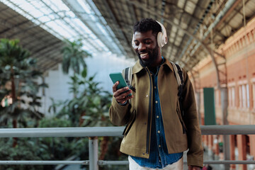 Tourist wearing headphones using smart phone in railway station, madrid