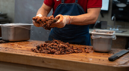 Chef is making minced beef. Minced beef sandwiches are a delicious and versatile meal option. They consist of ground beef that is seasoned and cooked, then placed between slices of bread, buns, rolls.