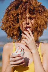 Young woman with curly hair enjoying ice cream on a sunny day by the sea