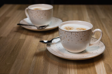 Two cups of cappuccino on a wooden table. Ready to drink.