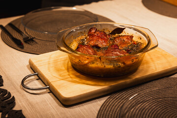 Pork shank served in a baking dish on a wooden board. Dinner dish served on the table. Culinary concept.