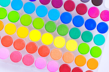 Essential tools for artists hobbyists, ready colorful paints palette of watercolors, arranged in a rainbow colors ready to spark creativity.