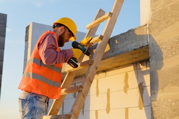 Construction worker using cordless drill on wooden ladder at building site © nazariykarkhut