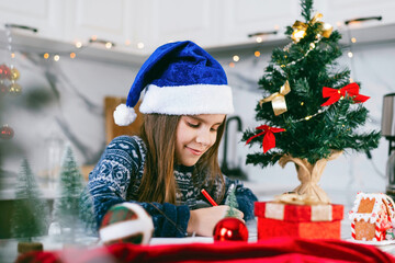 Happy toddler girl write a letter to Santa. Christmas holidays concept.