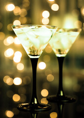 Two glasses of fresh cocktail with ice on black bokeh background. Trending green.