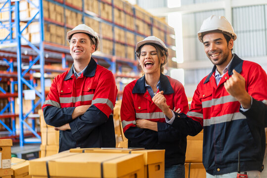 Warehouse team of industrial workers in red uniforms and safety helmets standing smiling teamwork and logistics concept, professional warehouse staff, supply chain, shipping, storage management