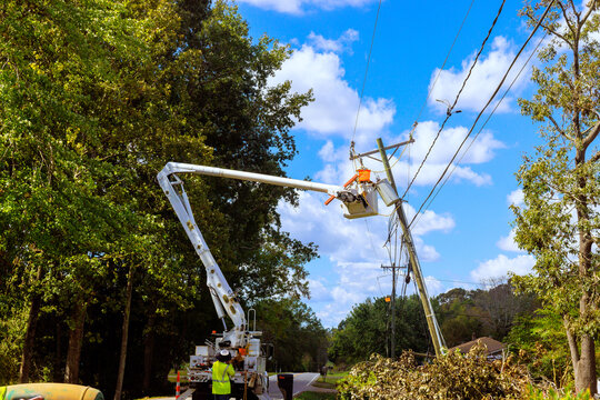Power line worker repairs installs equipment on utility pole using hydraulic lift.