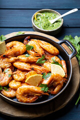  Fried shrimps with lemon and green on a round board vertical photo