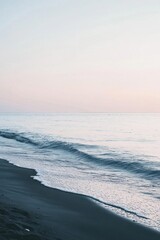 Serene beach scene at sunset with gentle waves and soft colors.