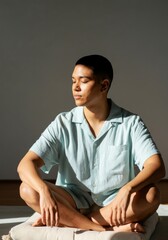 Obraz premium Calm Pacific Islander non-binary person meditating in sunlit room wearing light blue shirt
