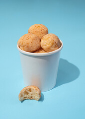 four Brazilian cheese breads - pao de queijo in the paper bucket on a blue background