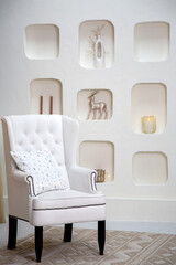 Modern minimalist interior featuring a white tufted armchair with a decorative pillow, set against...