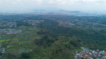 Green Hilly Highlands with Local Houses Facing Bandung City in Indonesia view from above