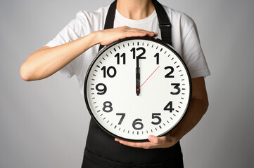 Cooking deadline concept. Woman chef in apron holding clock, white background with copy space
