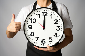 Cooking deadline concept. Woman chef in apron holding clock, white background with copy space