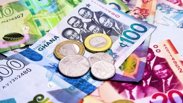 Camera panning 360 degrees around Ghanaian cedi notes and coins. Camera moving spinning rotating revolving around Scattered Ghana cedis notes on surface. Looping video
