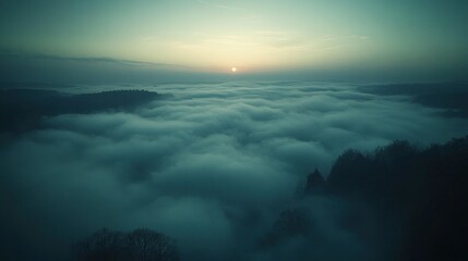 Fototapeta premium A serene landscape of fog covering trees at sunrise, evoking tranquility and reflection.