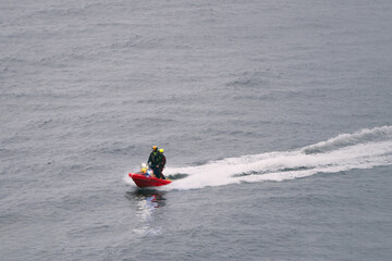 Lifeguard on red scooter patrolling the sea coast