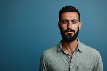 Obraz premium Serious bearded man in green shirt on blue background.