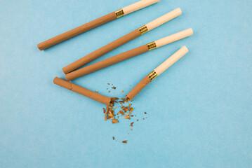 Several female cigarettes one broken. Blue background. Stop smoking concept.