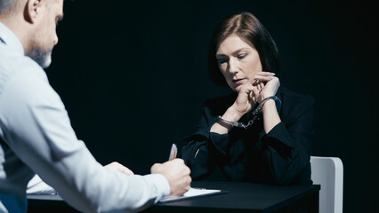 Handcuffed woman admits guilt while a police detective fills out the investigation report