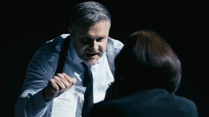 Angry investigator yells at a scared witness, showing an evidence bag, illustrating power abuse
