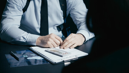 Police detective looks at a bribe offered by the crime suspect and takes the money, indicating...