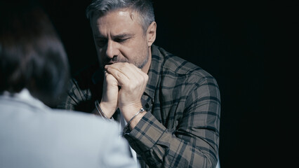 Handcuffed man confesses guilt in a crime, providing evidence to the police investigator