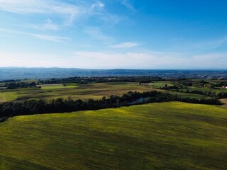 Fototapeta premium Scenic view of lush green fields and distant hills under a clear blue sky in the countryside