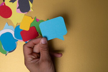 Hand holding a blue speech bubble representing a voice in a sea of opinions