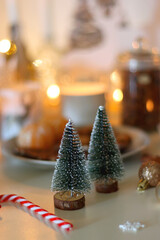 Various Christmas decorations, cookies, chocolate, nuts and tangerines, wine glasses and lit candles on the table. Holiday hygge at home. Selective focus.