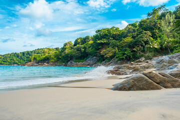 Tropical beach with turquoise waters, sandy shore, palm trees, rocks and green foliage under a bright blue sky with nobody. Freedom beach in Phuket island, Thailand. Summer travel destination in Asia
