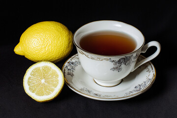 Warm tea served with fresh lemon on a dark background