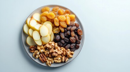 A colorful and nutritious snack platter showcases fresh apple slices, dried apricots, raisins, walnuts, and pecans. This arrangement offers a perfect balance of flavors and textures