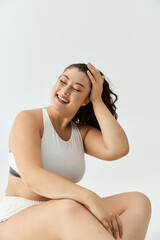 Fototapeta premium Young plus size woman embraces her beauty while posing cheerfully in trendy underwear.