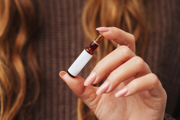 Glass ampoule background. Hyaluronic acid serum in woman fingers. Cosmetic product advertisment....
