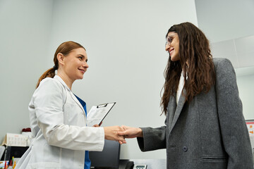 Fototapeta premium A gynecologist discusses health matters with a female patient in a clinic, ensuring care.