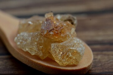 A food macro shot of Acacia plant in a wooden spoon isolated on a wooden background.