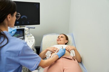 A gynecologist performs a medical checkup on a female patient in a contemporary clinic.