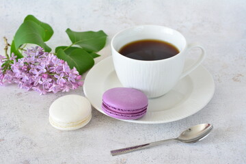 a cup of coffee next to a lilac branch and purple and white macaroons 